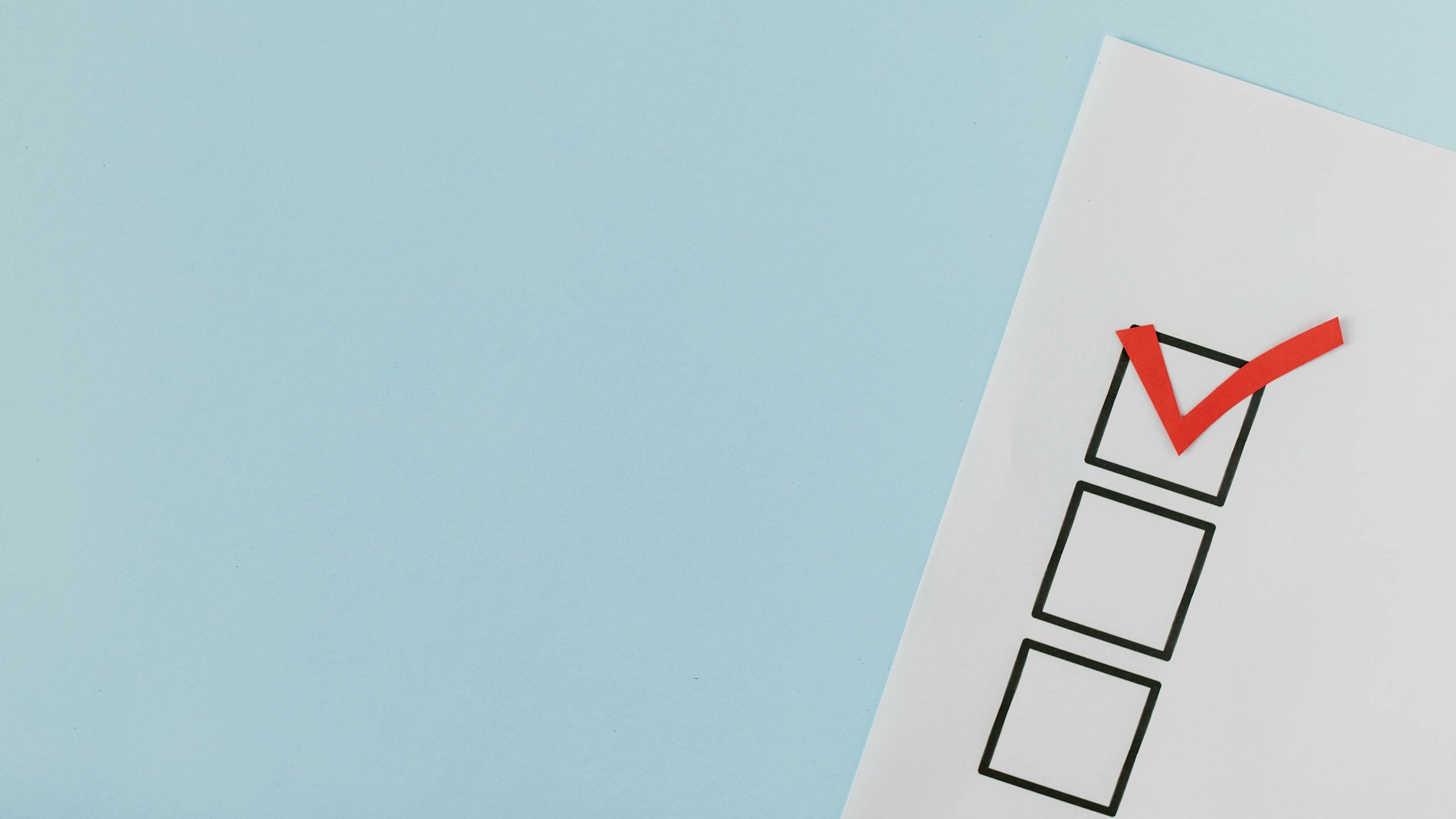 A checklist with a red checkmark symbolizing a completed task on a pastel blue background.